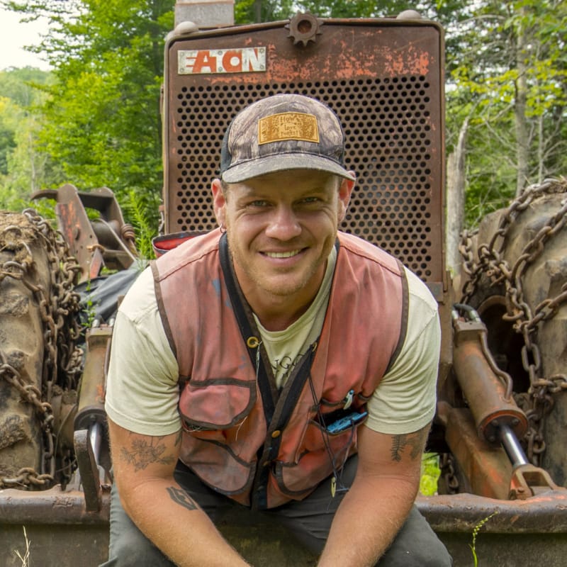 Forester, Author, and Creator poses outdoors wearing a high-vis vest.
