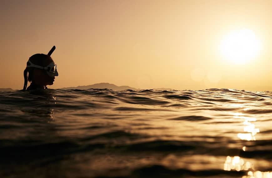 Image: A woman wearing a snorkel treading in the water at sunset, much like the VR do when spotting sharks for surfers in Réunion.