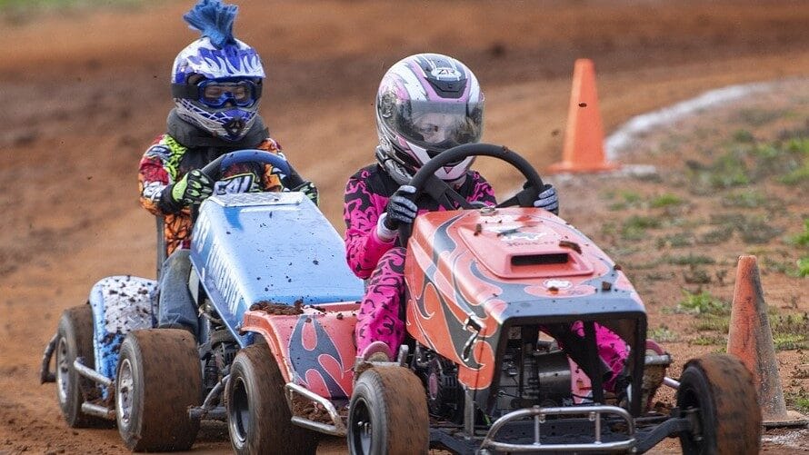 Image: Two people competing in a lawn mower race