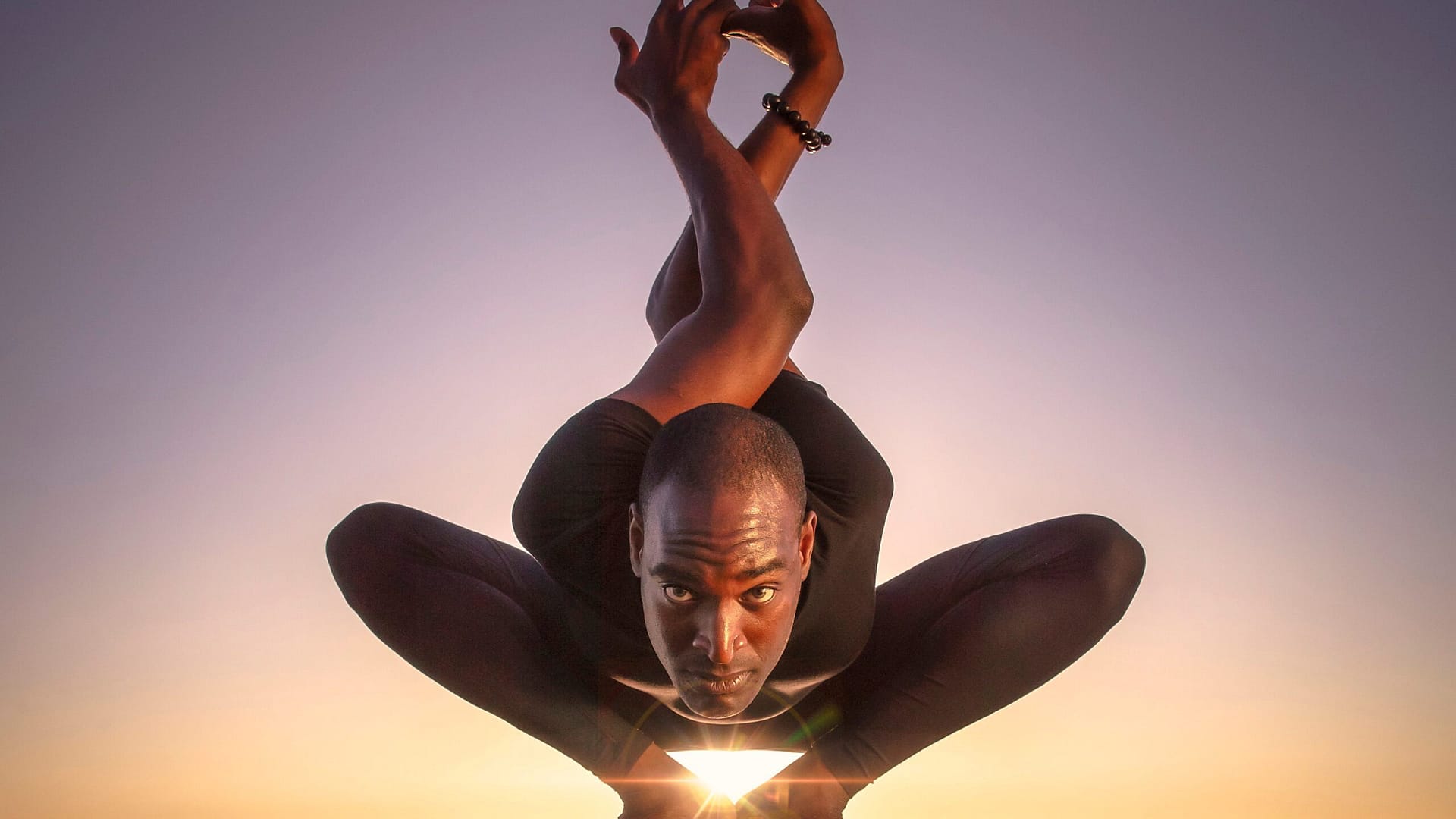 Image: Troy James crouching with his arms twisted behind his head. 