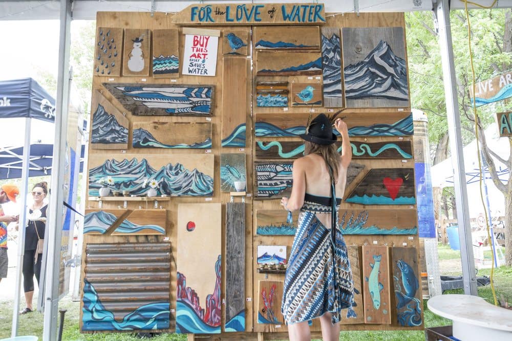 Image: Artist and their mural consisting of small paintings to sell off to raise money for Water Conservation