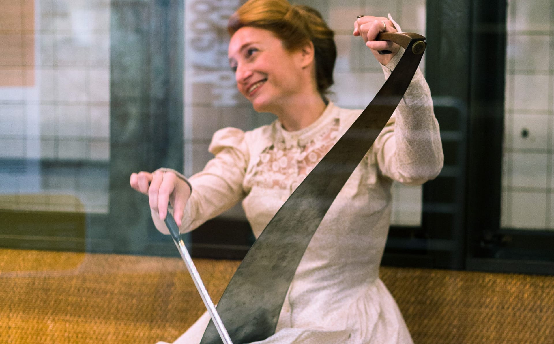 Image: Nataliz in a white gown smiling and playing the musical saw!