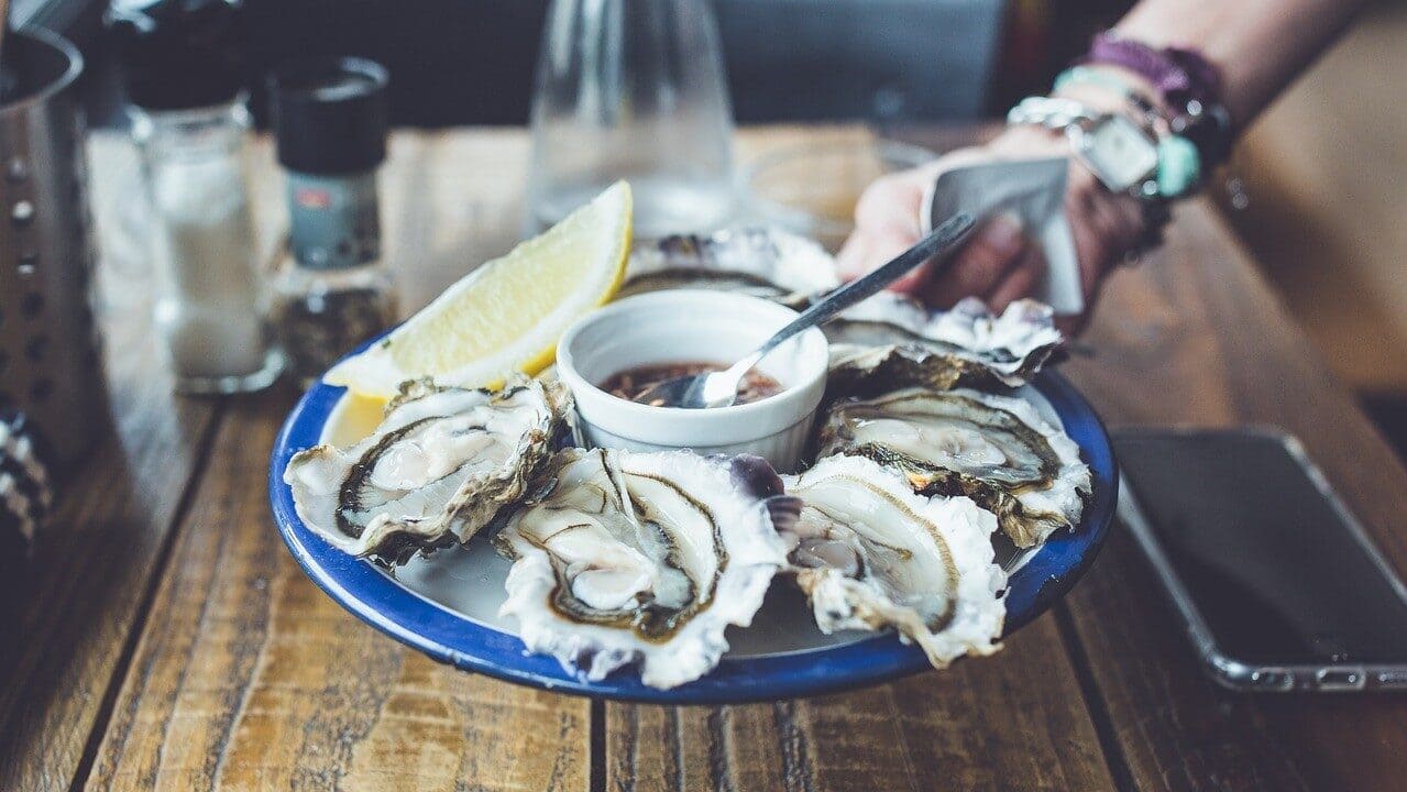 Image: someone handing over a plate of oysters