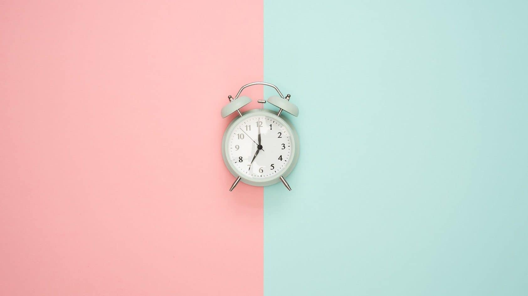 Image: Alarm clock on a background with two different colors splitting the image down the middle representing two ways of seeing time