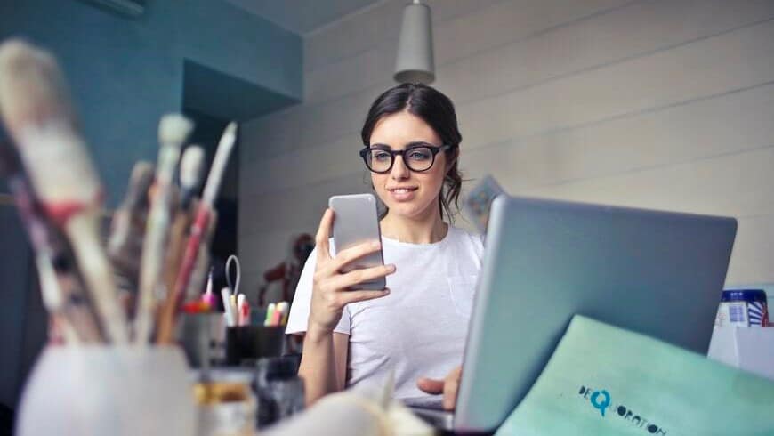 Image: A woman in a white shirt looking at her phone, trying to stop procrastinating.
