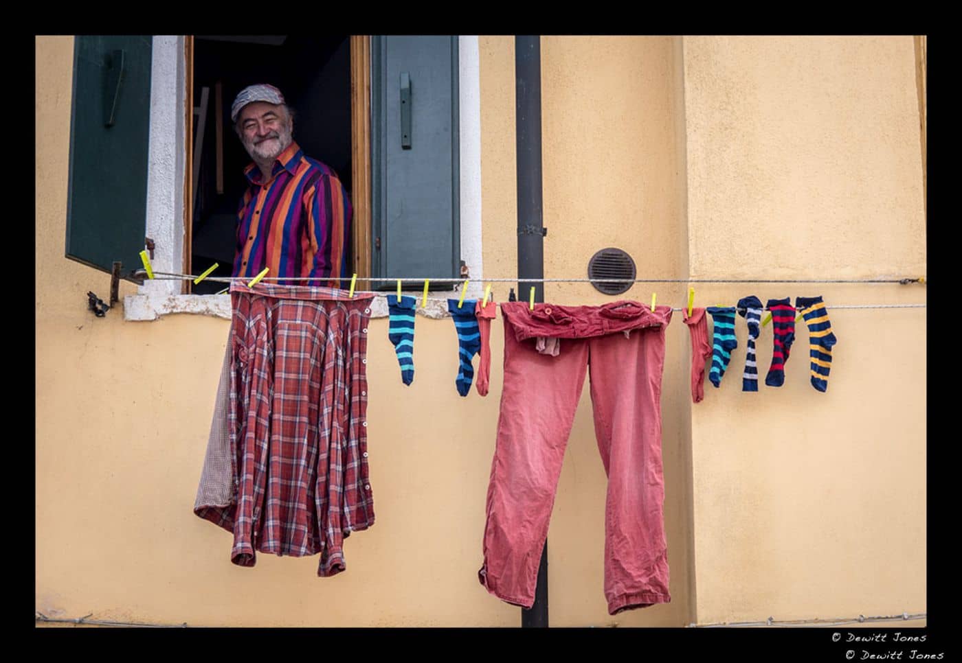 Image: Man smiles out of an open window with laundry hanging on the line in front of him taken by Dewitt Jones