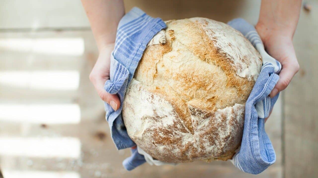 Image: A loaf of bread being gently held out in a towel