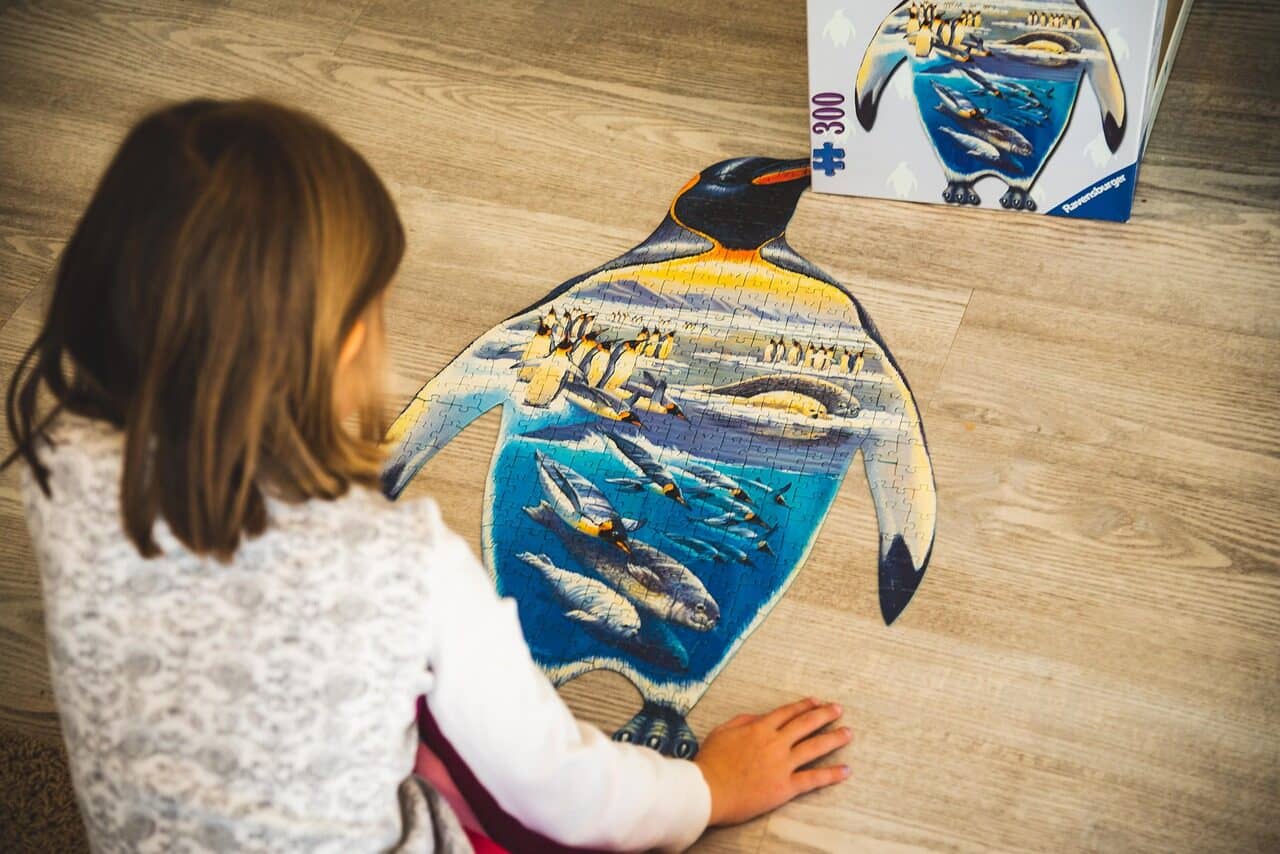 Image: Young child putting together a jigsaw puzzle shaped like a penguin