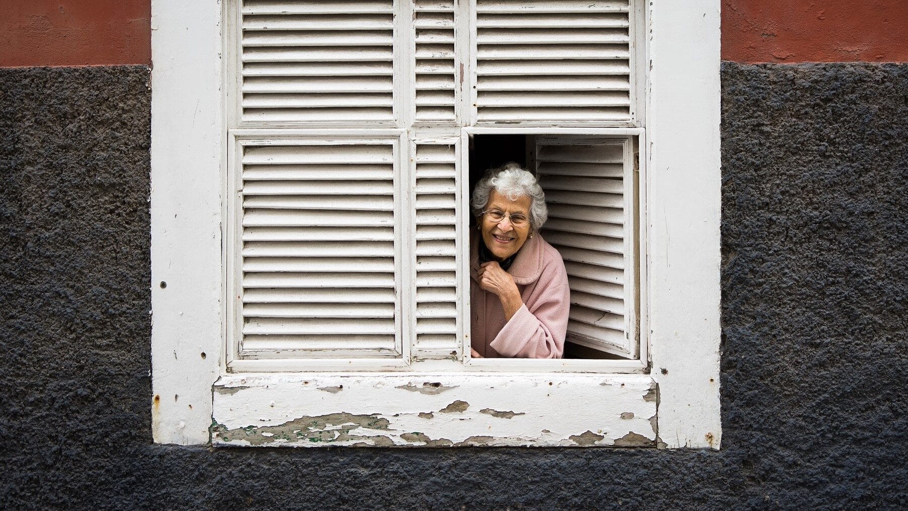 Image: Elderly woman peering out her shuttered windows smiling! 