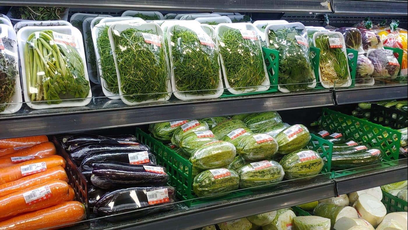 Image: A grocery store aisle of vegetables, all covered in plastic packaging. 