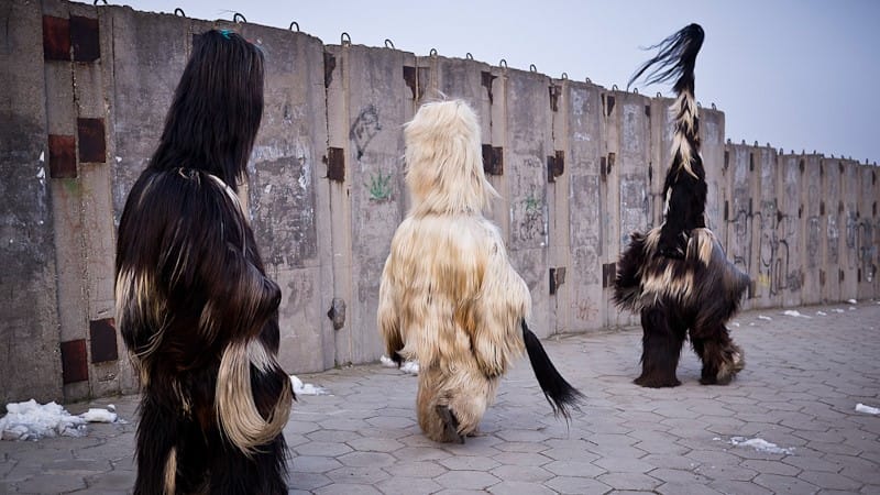 Image: Three Kukeri dancers walking through the streets of Bulgaria.
