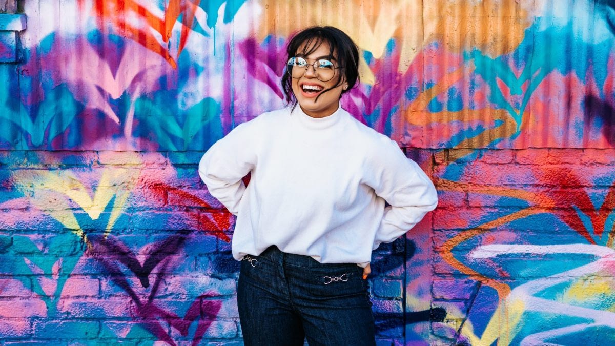 Smiling woman in glasses against bright wall