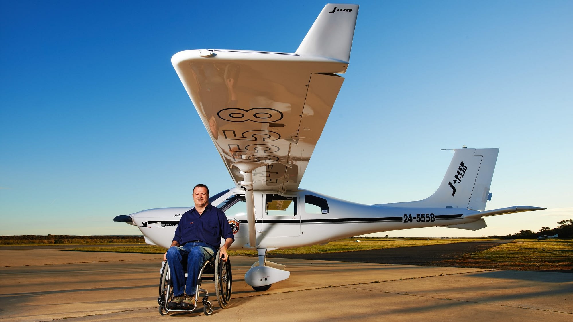 Image: Dave Jacka in his wheelchair in front of his plane