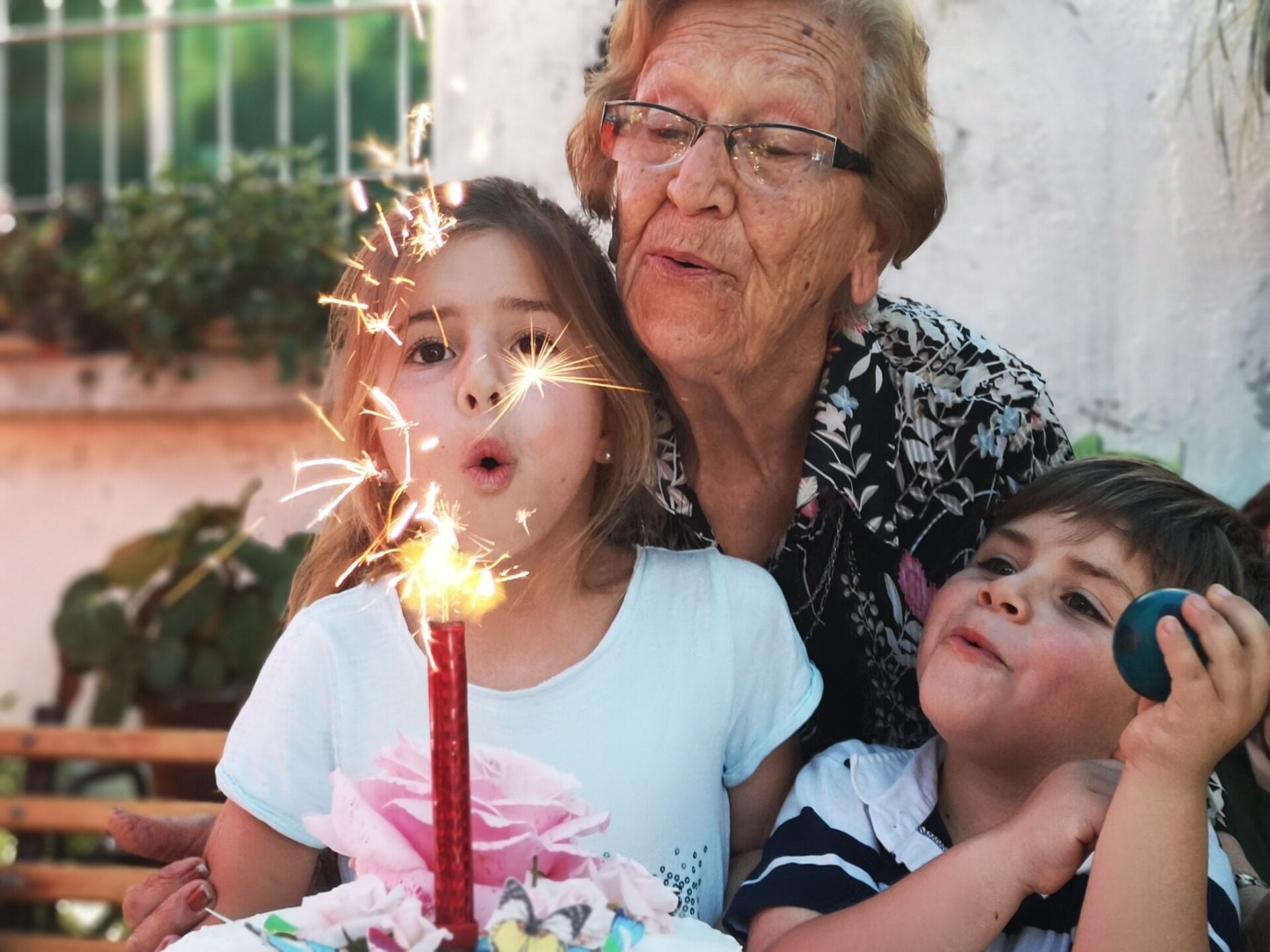 Image: Grandmother Blowing out candles with her grandchildren--representing how we may be able to inherit trauma across generations
