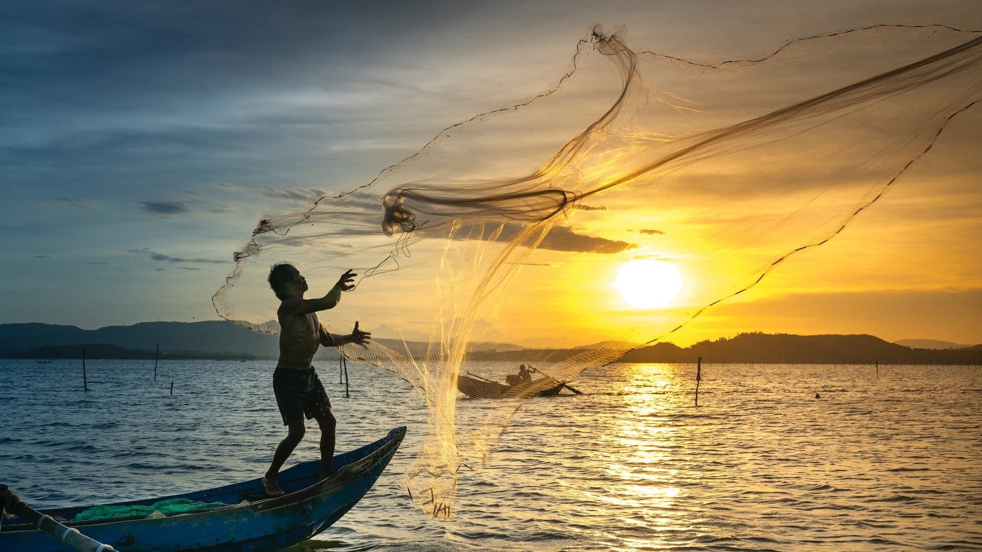 Image: Man throwing a fishing net at sunset