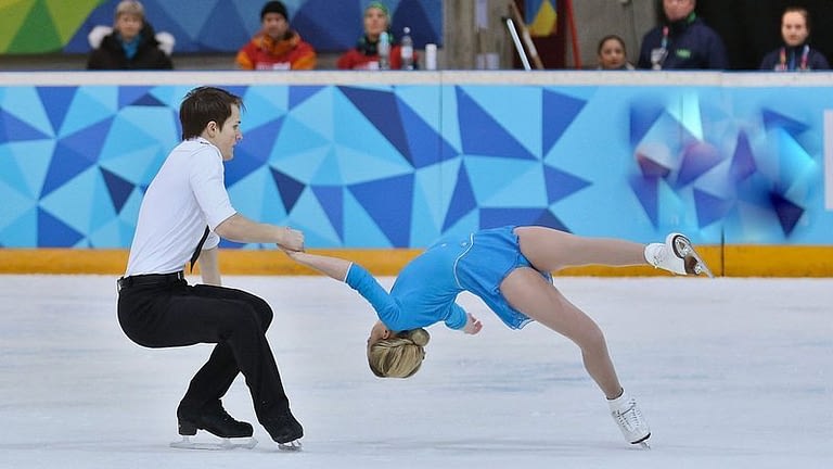 Image: Skating pair with man working very hard and woman in a death spiral
