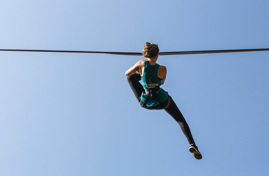 Image: A woman hanging from a slackline while slacklining