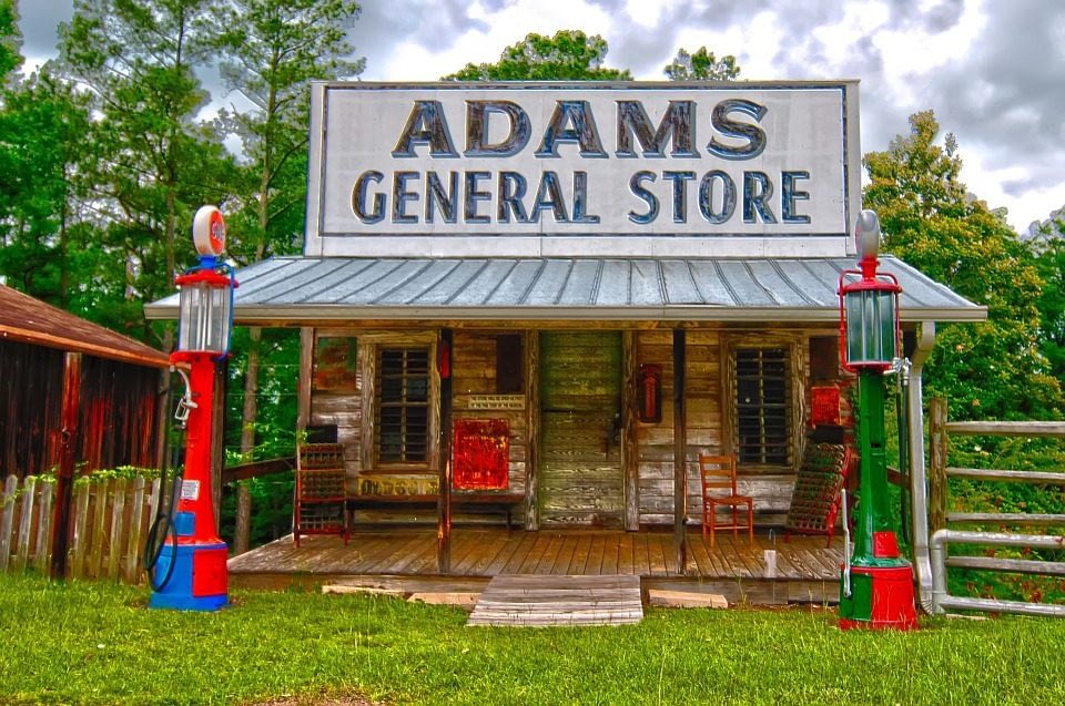 Image: A small building with a large sign reading "Adam's General Store", like the one in the backyard wonders of Cowtown Keeylocko
