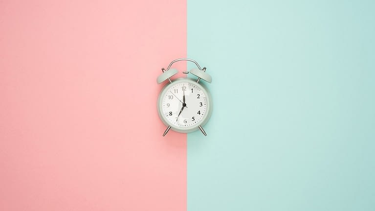 Image: Alarm clock on a background with two different colors splitting the image down the middle