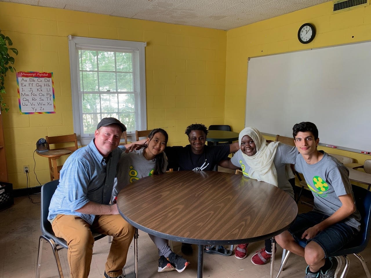 Image: Brad and Robby around a table with students from Fugees Academy 