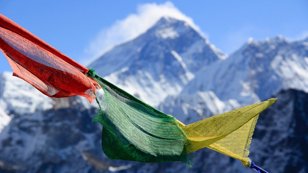 Image: the peak of Mount Everest behind colorful Tibetan prayer flags