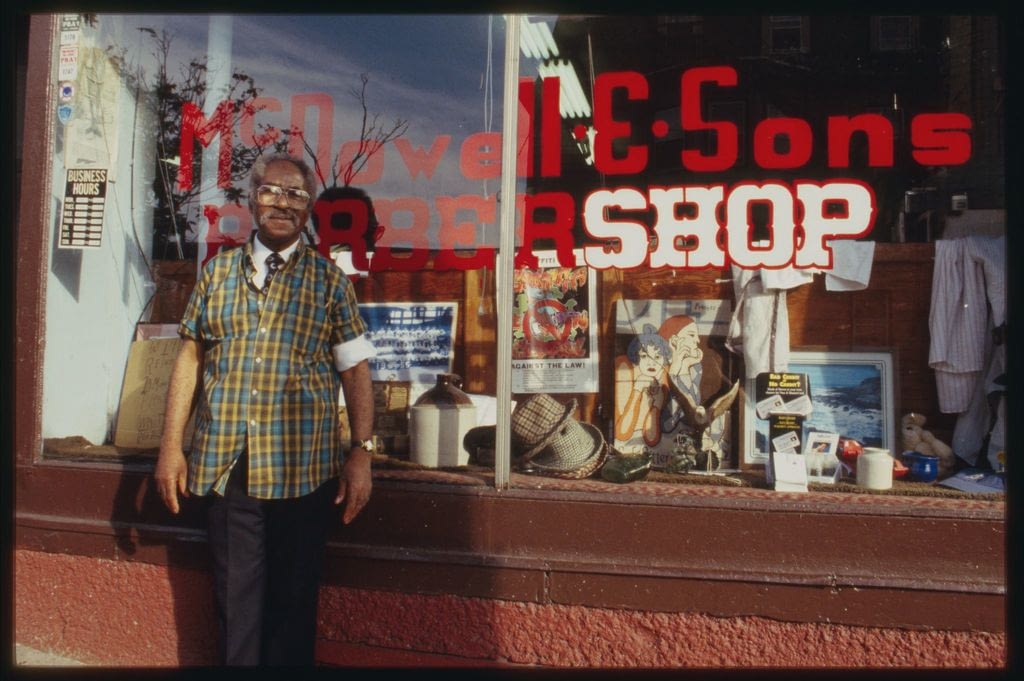 Image: Older gentleman stands in front of his barber shop
