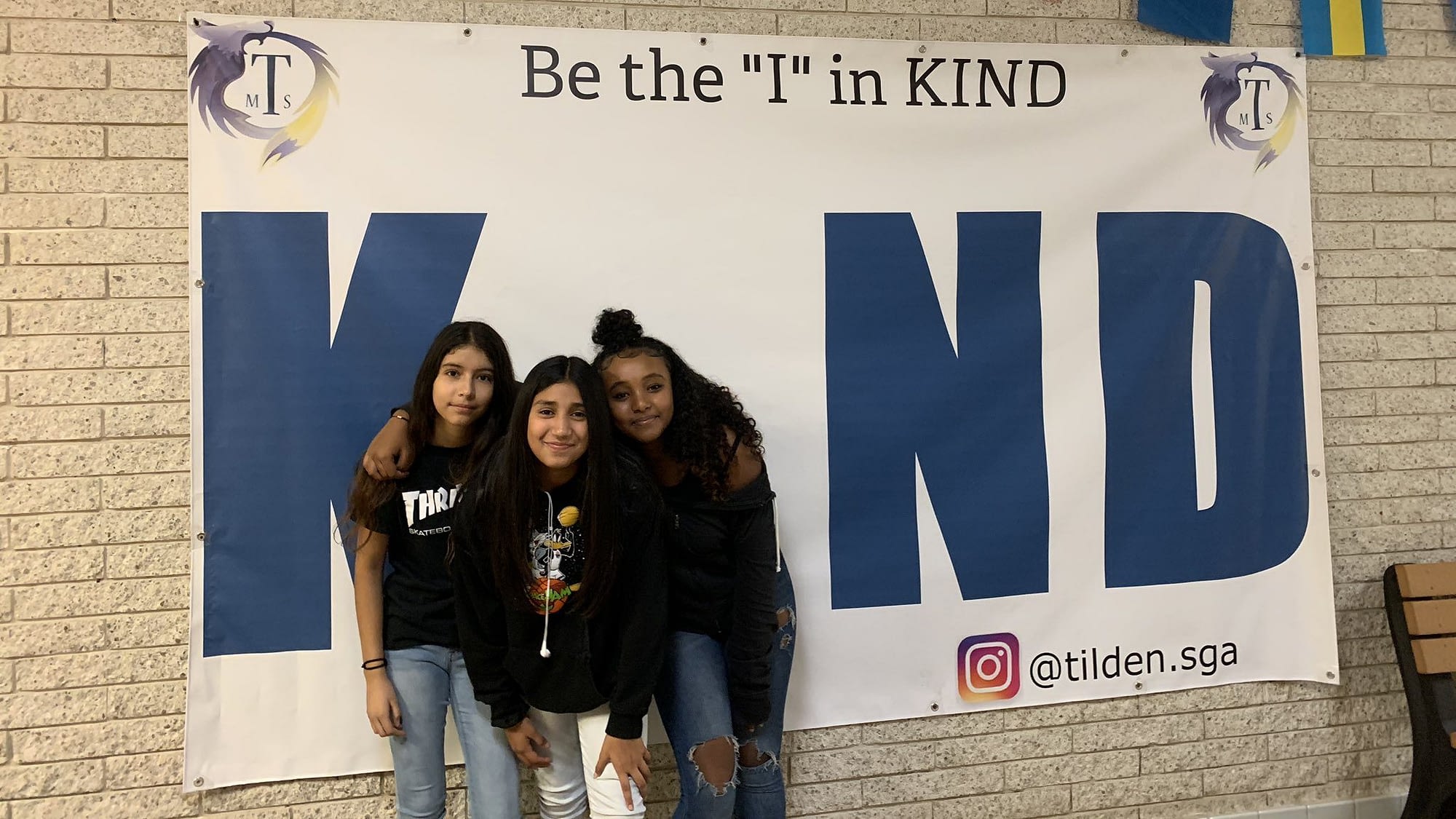 Image: Tilden Middle School Students in front of a poster that says "be the I in kind"