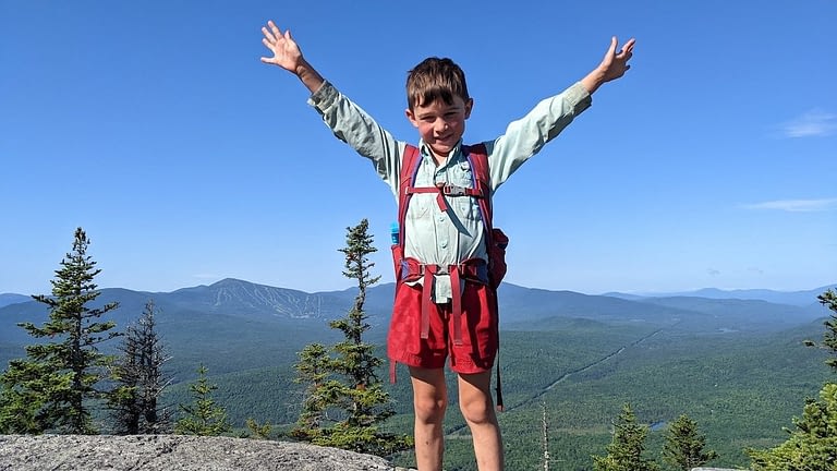 Image: 5 Year Old Harvey Sutton raising his arms to the sky on top of a mountain on the Appalachian trail.